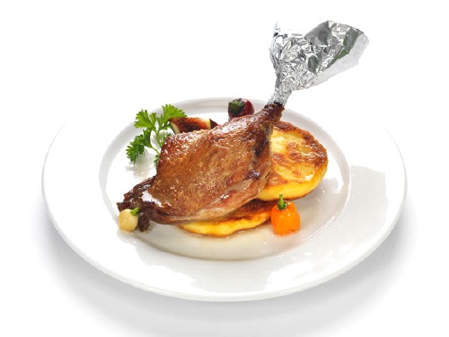 Crispy duck leg roasted on a bed of apples, with potato roundel